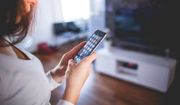 Woman browsing smartphone indoors, highlighting modern technology and communication in a cozy home setting.